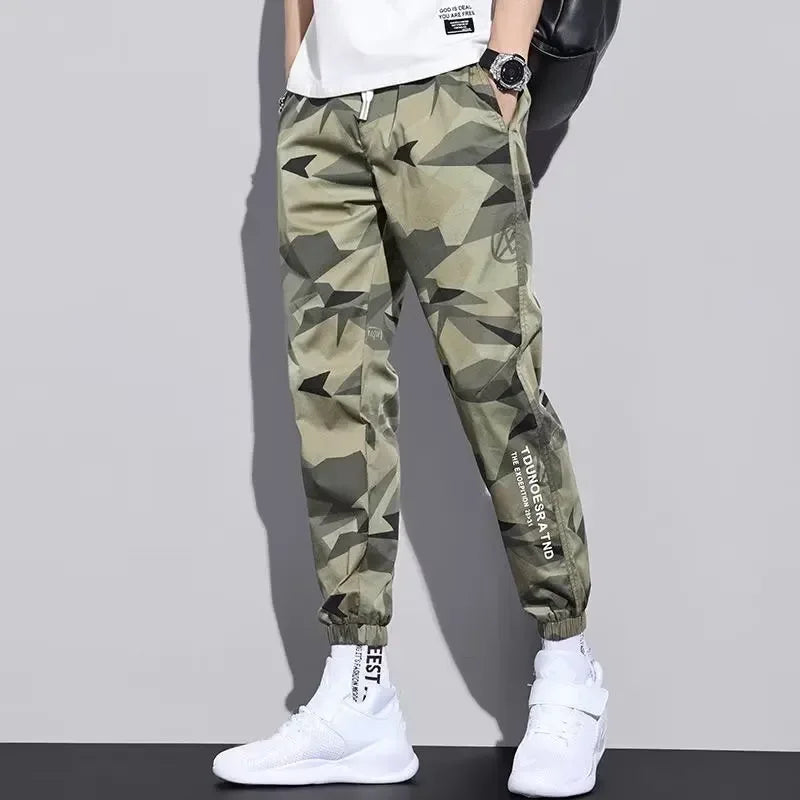 Camouflage pants worn by a person on a plain background