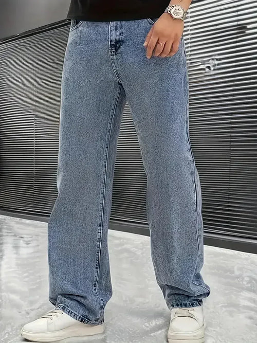 Person wearing light blue jeans and white sneakers against a metallic background