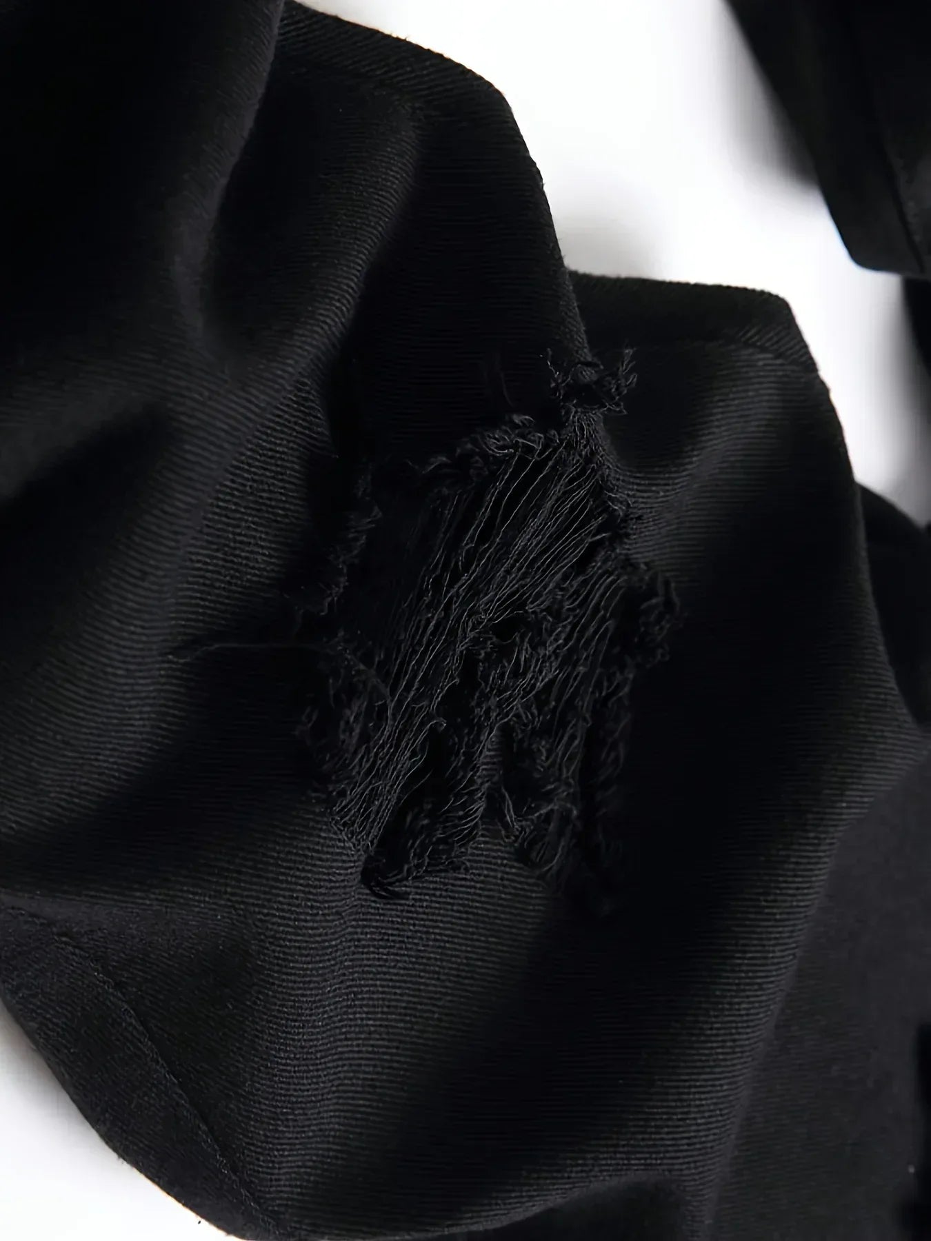 Close-up of a black fabric with tassels on a white background
