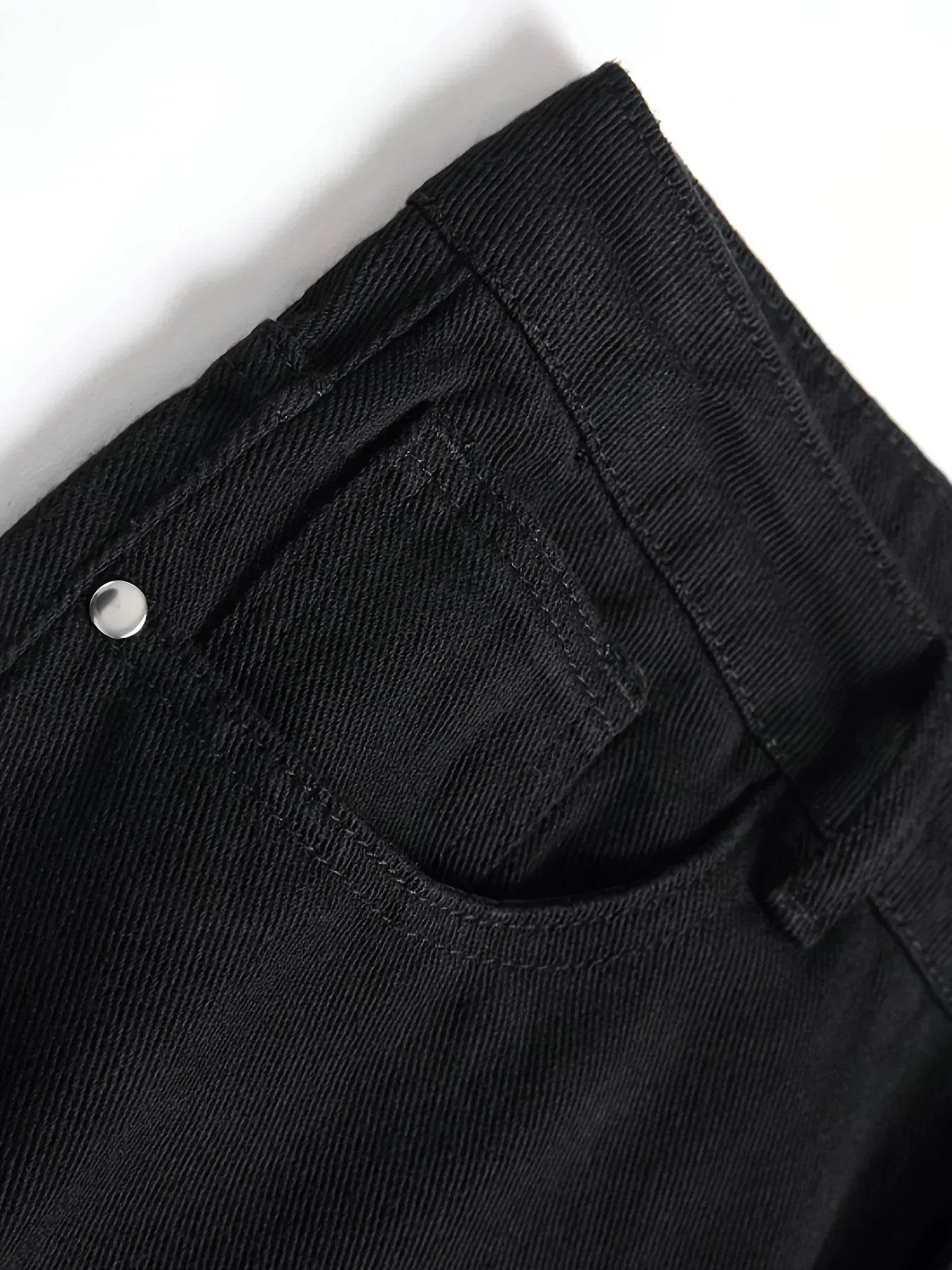 Close-up of black pants with a button on a white background