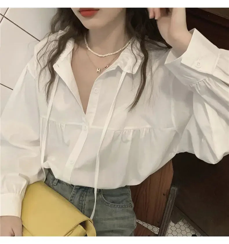 Person wearing a white blouse with puffed sleeves in an indoor setting