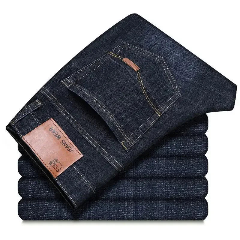 Stack of folded dark blue jeans with a brand label on a white background