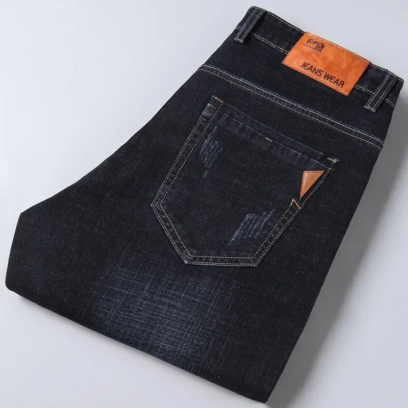 Folded pair of dark blue jeans with a brand label on a light gray background