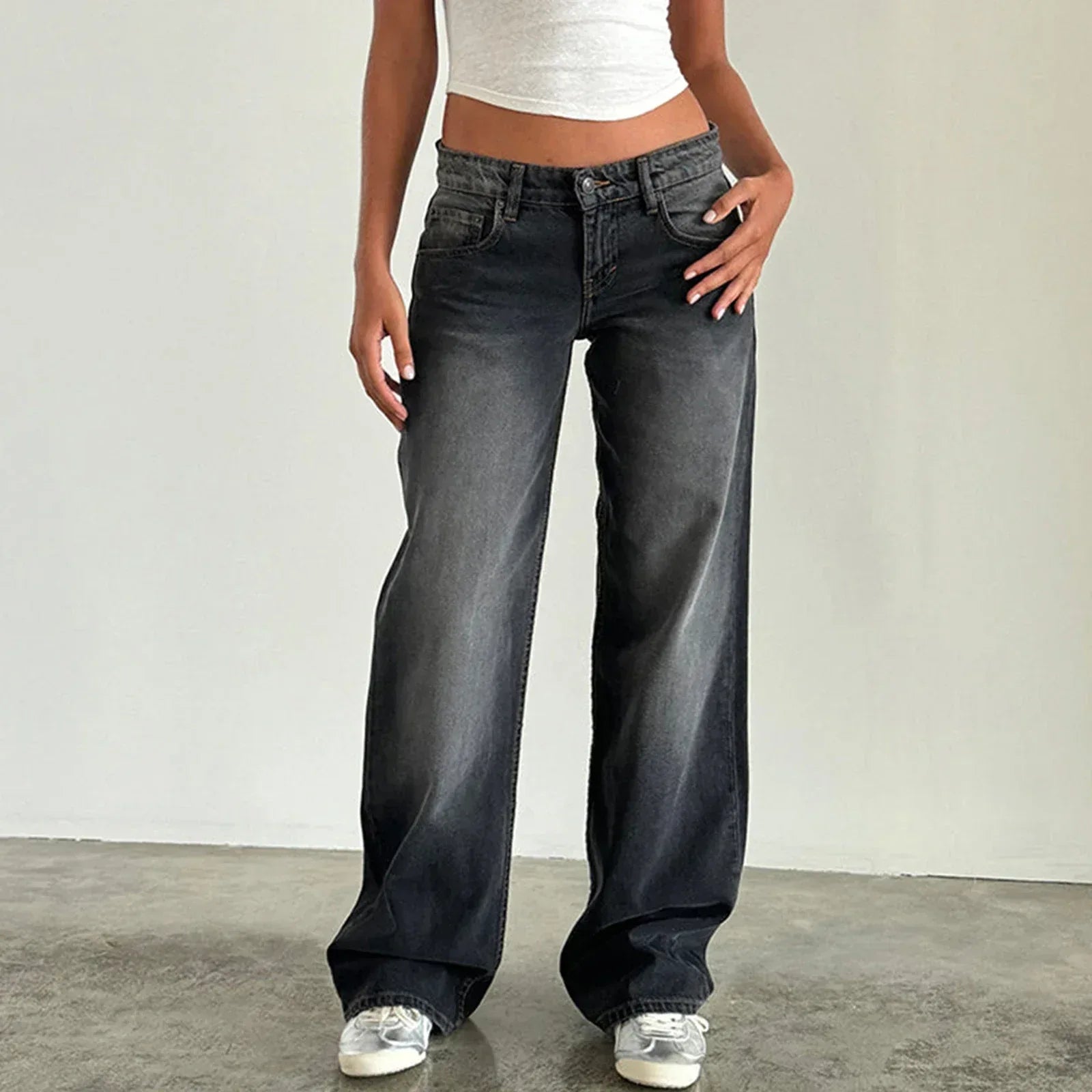 Person wearing black wide-leg jeans and a white crop top against a plain background