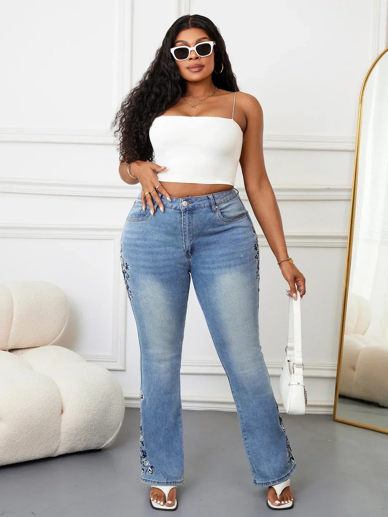 Woman wearing a white top and blue jeans in a minimalistic room.