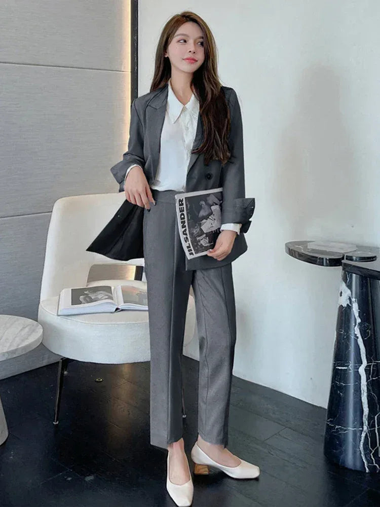 Woman in a gray suit holding a magazine in an indoor setting