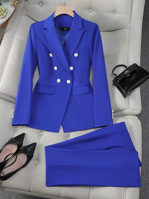Blue suit jacket and pants on a gray chair with black shoes and handbag.