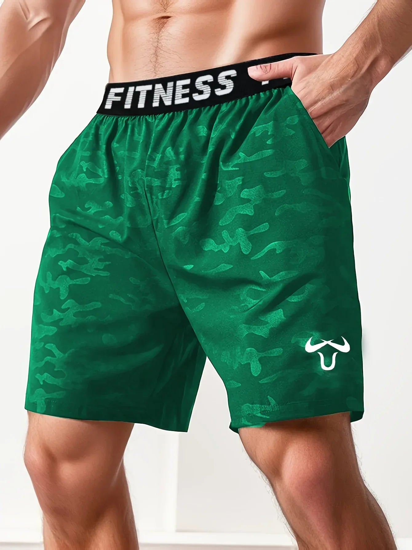 Green camouflage fitness shorts with 'Fitness' waistband on a person against a neutral background
