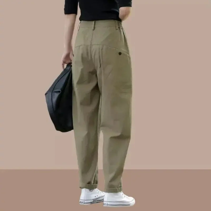 Person wearing beige pants holding a black bag on a beige background