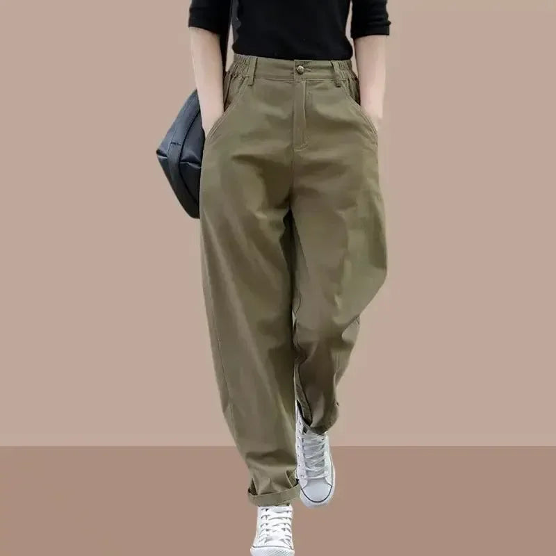 Person wearing olive green pants with a plain background