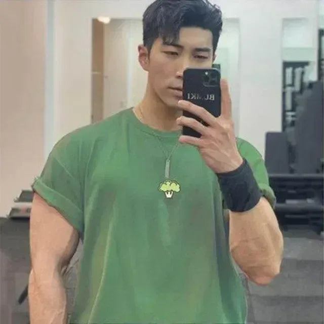 Man in green t-shirt taking a mirror selfie in an indoor setting
