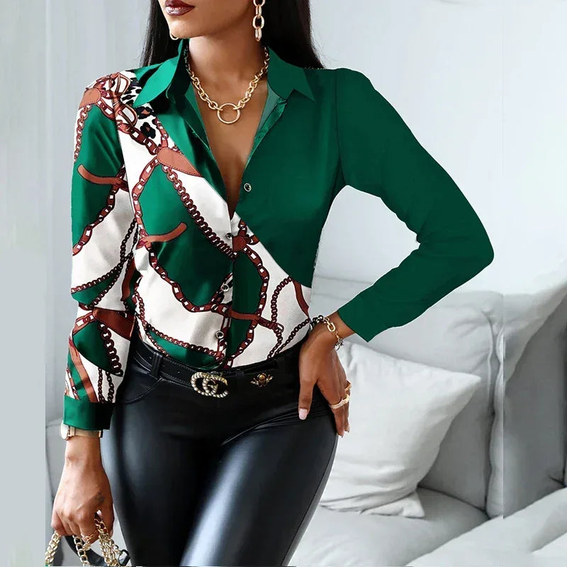 Woman wearing a green and patterned blouse with black pants in a living room setting.
