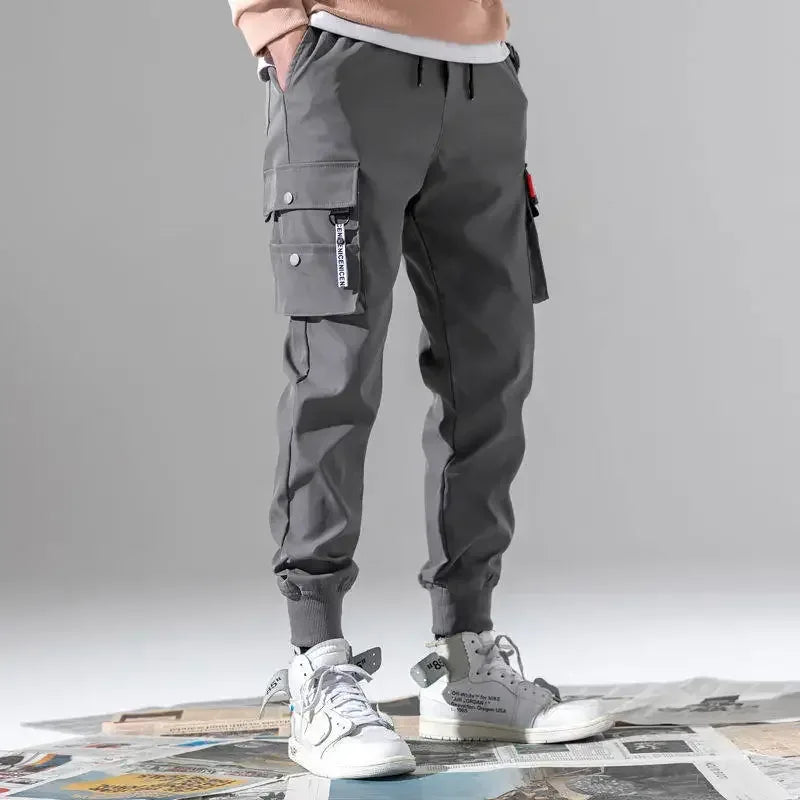 Person wearing gray cargo pants with multiple pockets on a neutral background