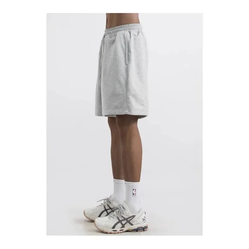 Person wearing gray shorts and white sneakers on a white background