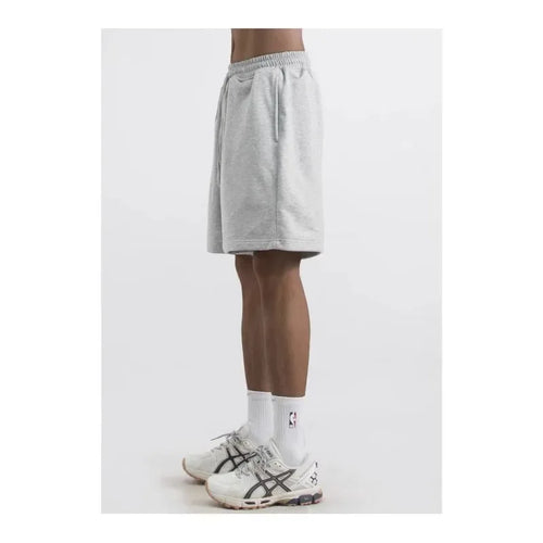 Person wearing gray shorts and white sneakers on a white background