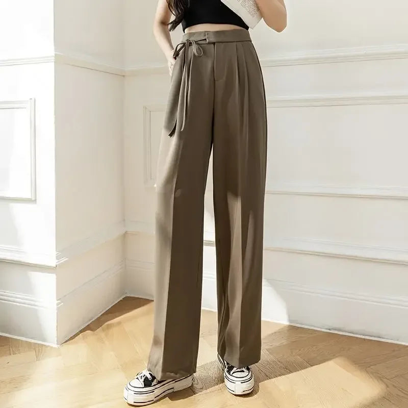 Person wearing brown high-waisted pants with a belt in a bright room.
