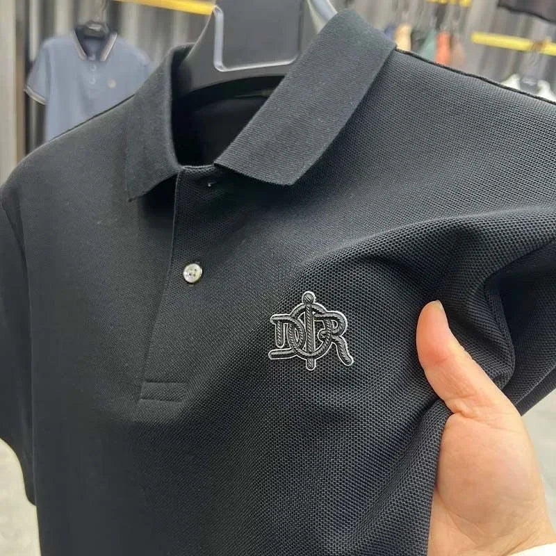 Black polo shirt with a logo held by a hand, on a blurred background