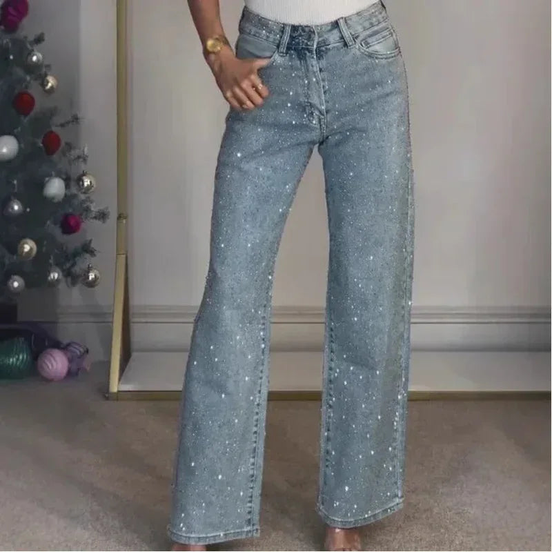 Person wearing sparkly blue jeans standing in front of a decorated Christmas tree.