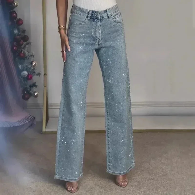 Person wearing light blue flared jeans in a room with a decorated Christmas tree.
