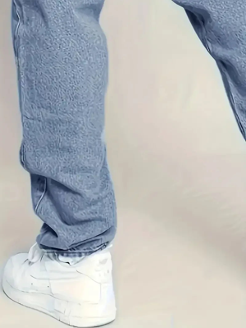 Person wearing light blue jeans and white sneakers on a plain background