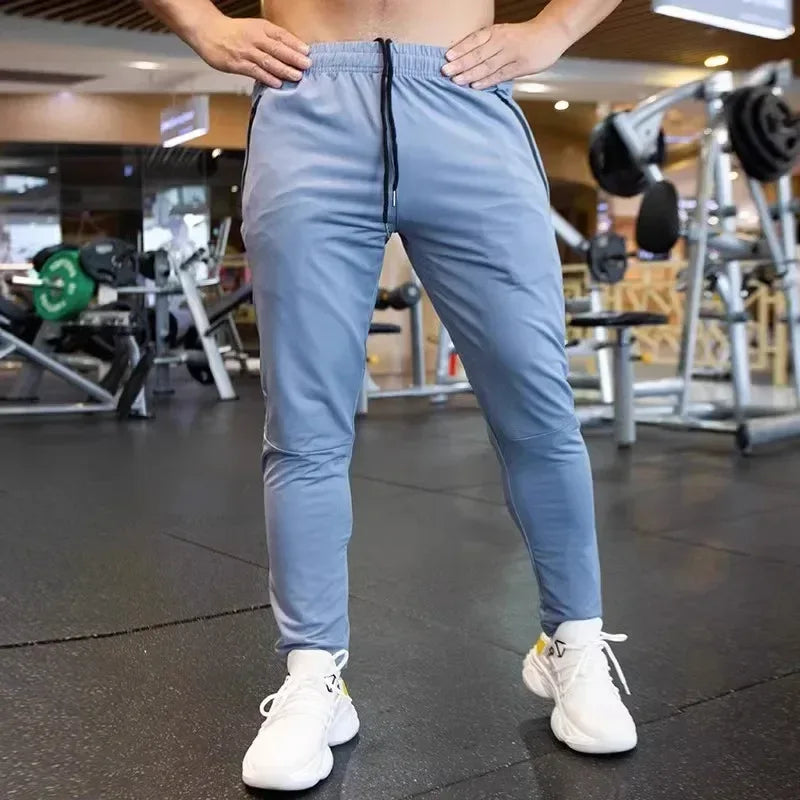 Person wearing light blue athletic pants and white sneakers in a gym setting