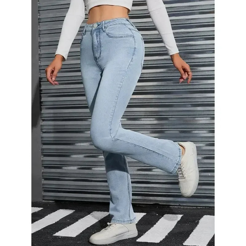 Person wearing light blue jeans and white sneakers in front of a metallic wall.