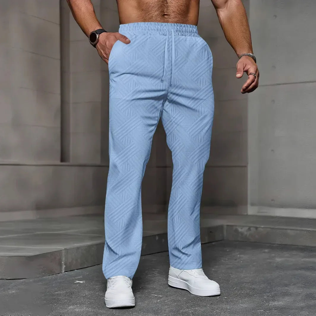 Person wearing light blue textured pants and white shoes against a gray concrete wall.