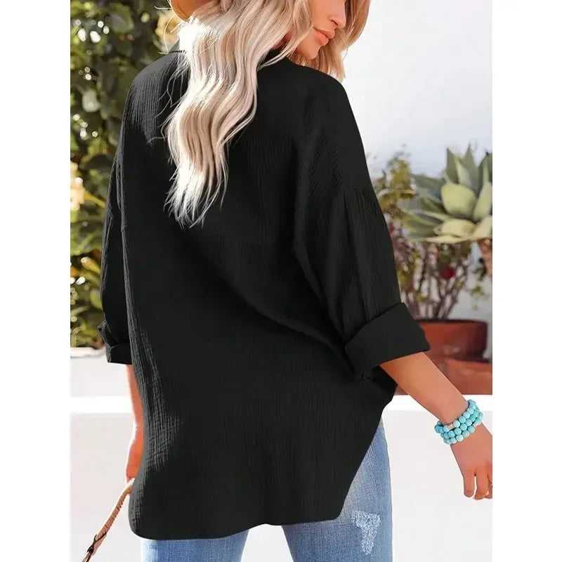 Person wearing a black oversized shirt with a blurred outdoor background