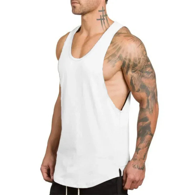 Man wearing a white tank top with tattoos on arms against a white background