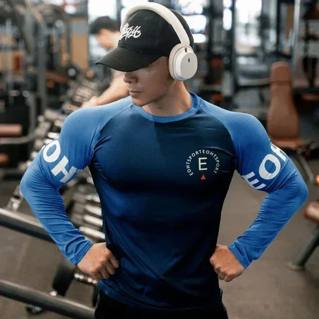 Person wearing a blue athletic shirt with branding in a gym setting