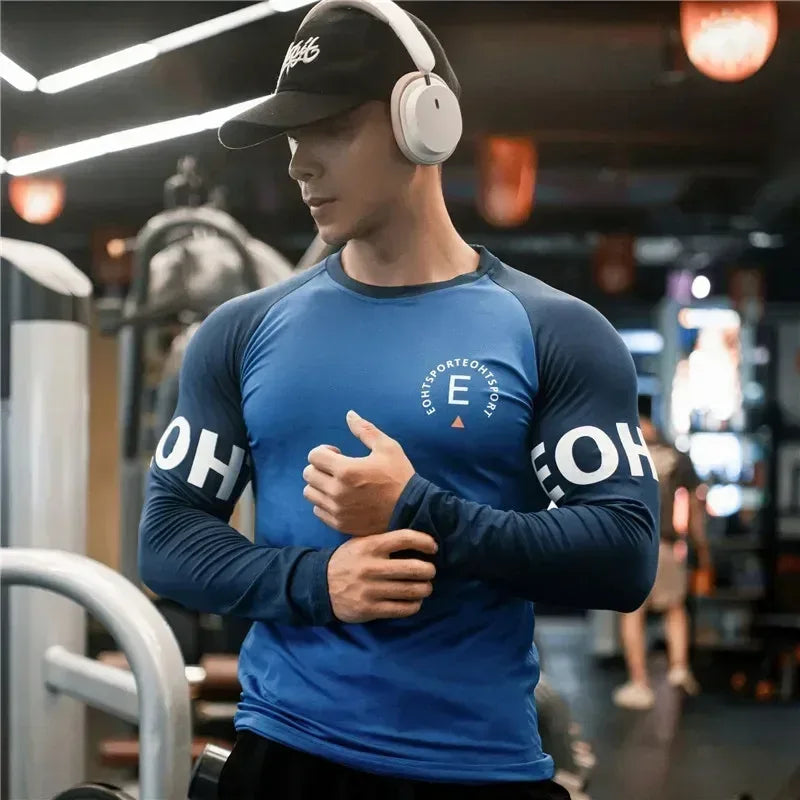 Man wearing a blue athletic shirt with branding in a gym setting