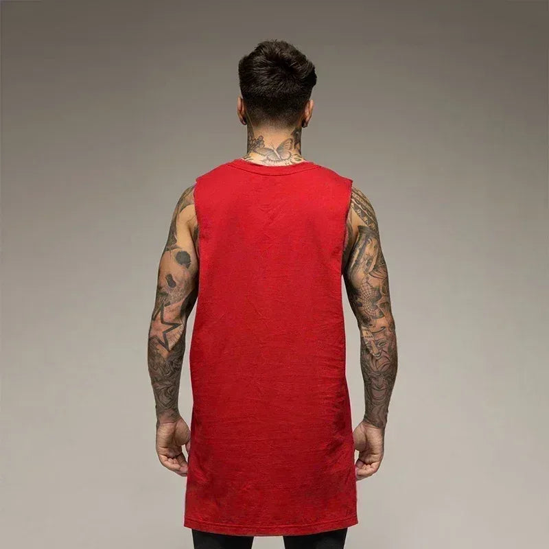 Person wearing a red sleeveless shirt with tattoos on arms against a gray background