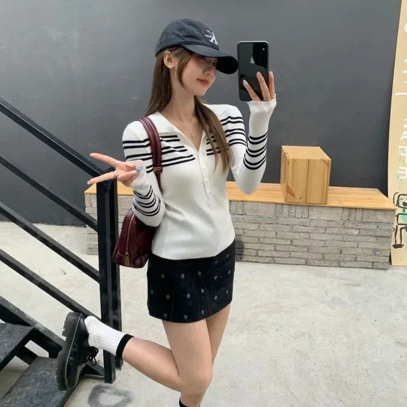 Woman taking a selfie on stairs wearing a striped sweater and cap