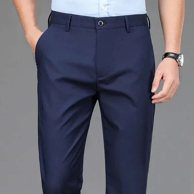 Navy blue dress pants worn by a person on a gray background