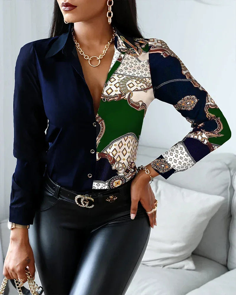 Woman wearing a patterned blouse with a navy blazer and black pants, sitting on a white couch.