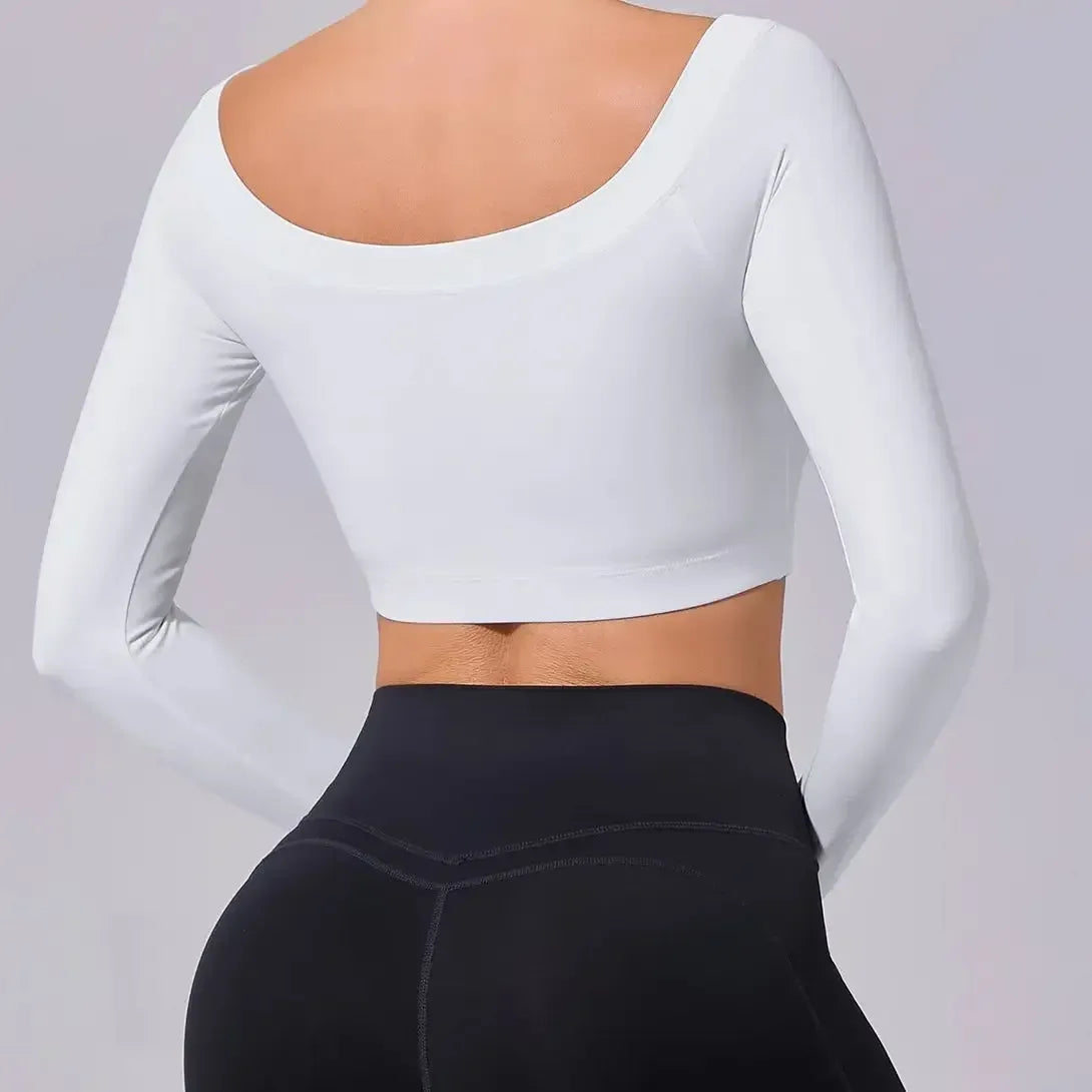 White long-sleeve crop top and black leggings on a plain background