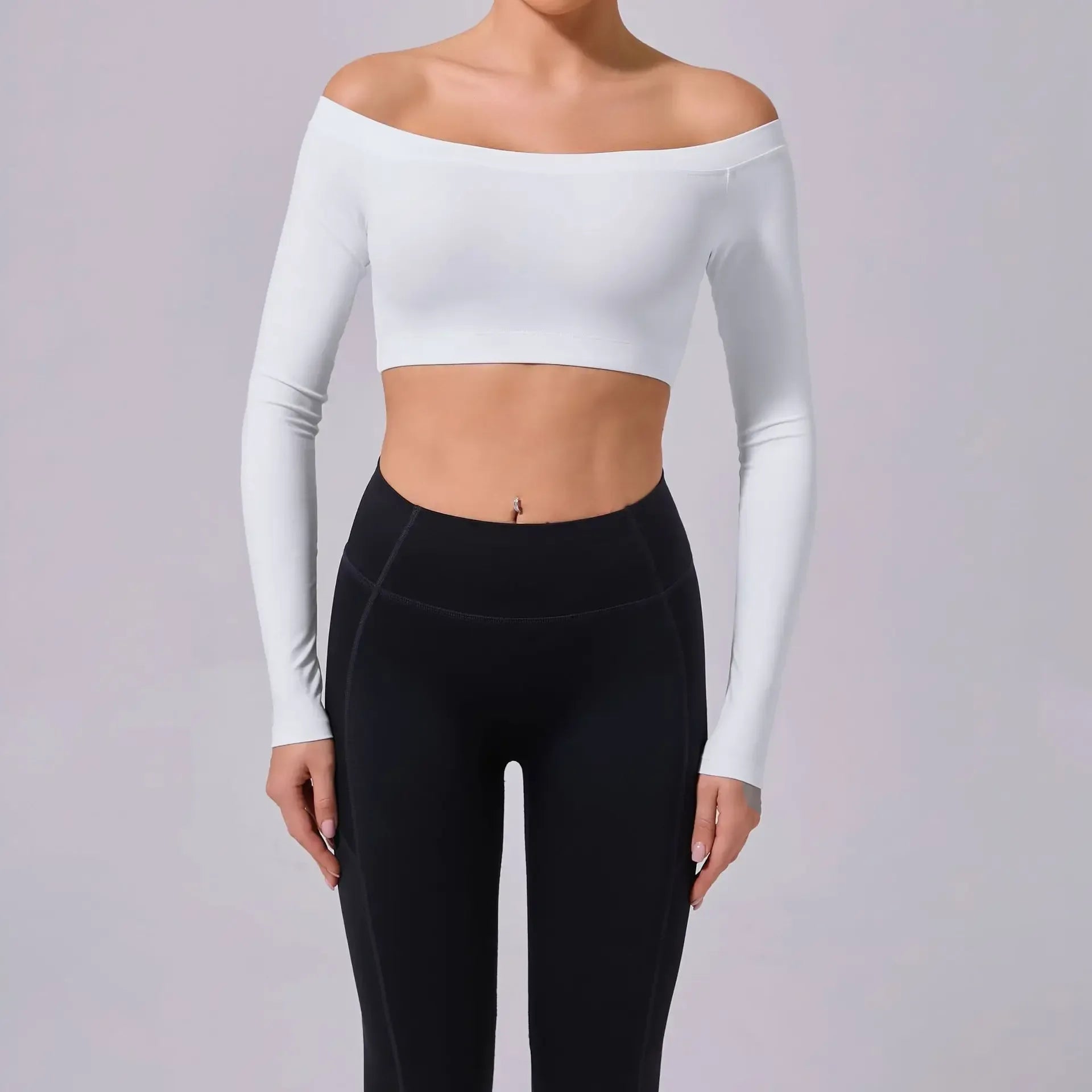 Person wearing a white long-sleeve crop top and black leggings on a light gray background