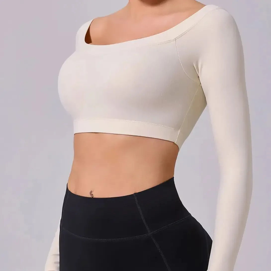 Person wearing a white long-sleeve crop top and black leggings on a plain background