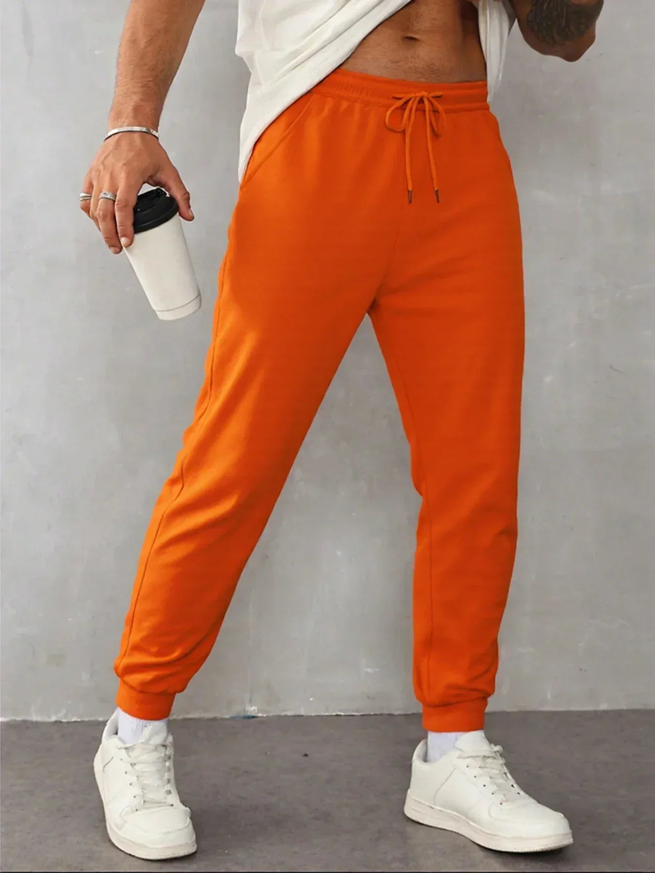 Person wearing bright orange sweatpants with a plain background