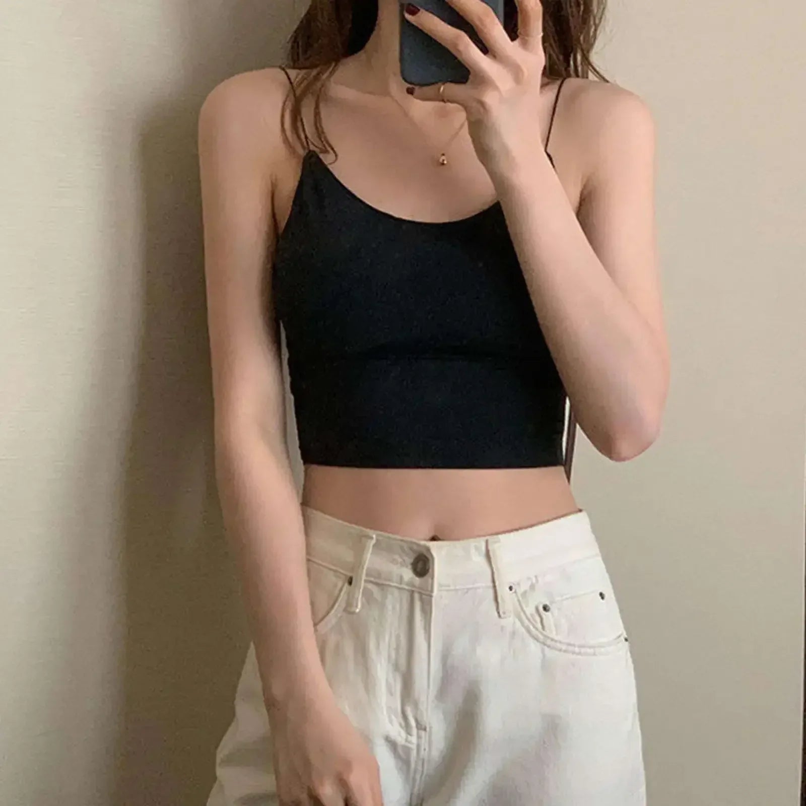 Person wearing a black crop top and white pants against a plain background