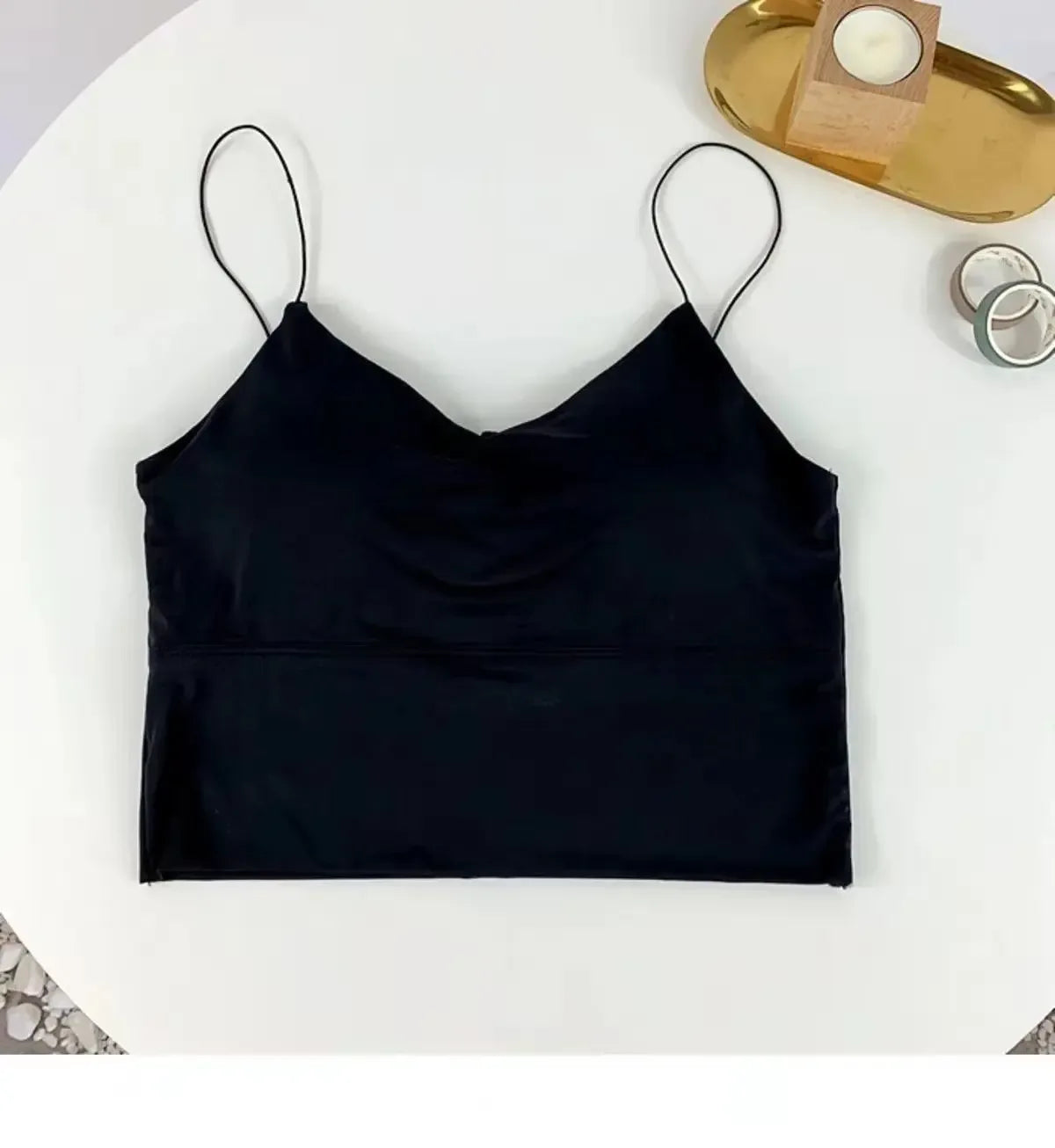 Black satin camisole on a white surface with decorative items in the background