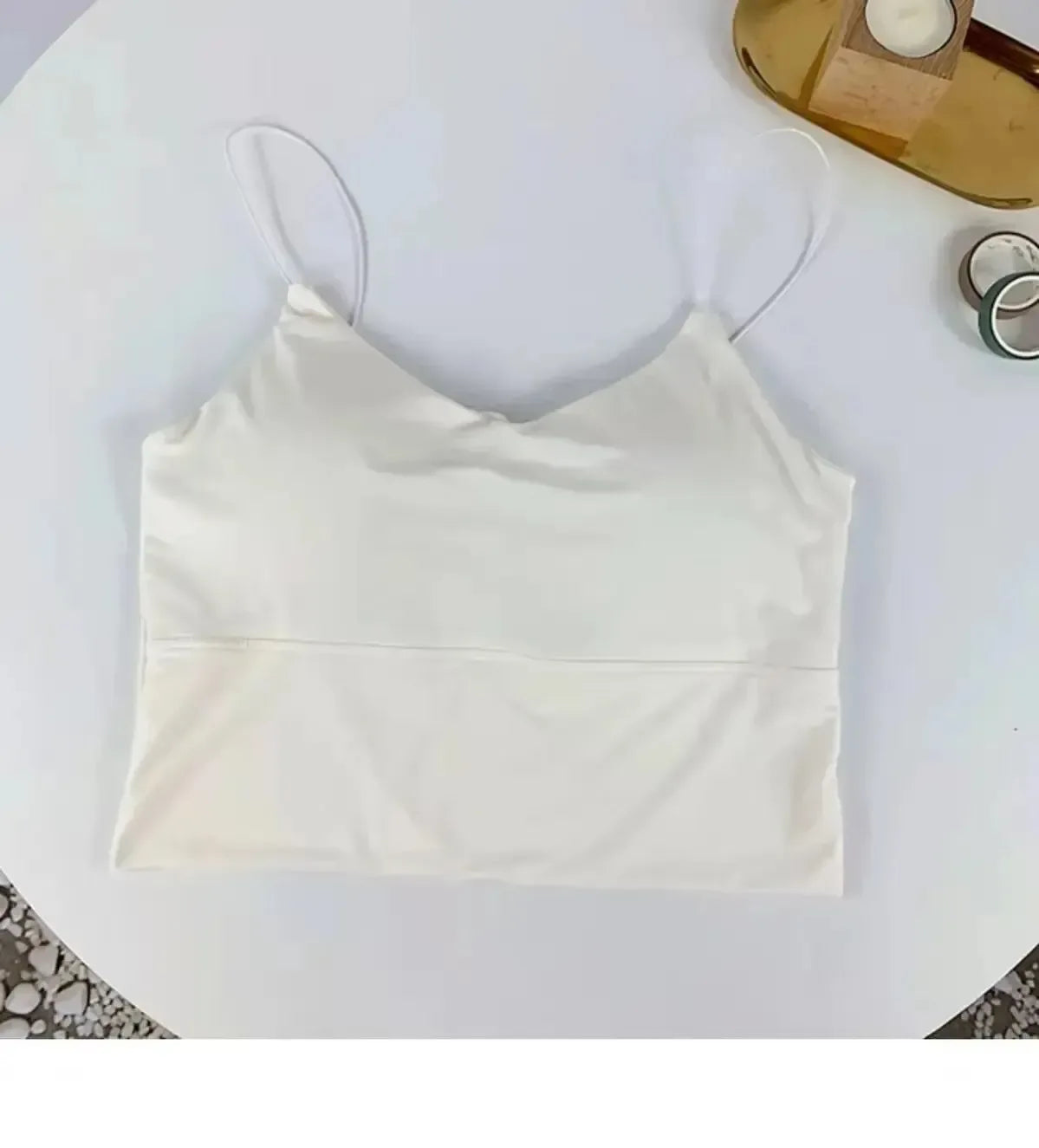 White satin camisole on a white surface with a blurred background