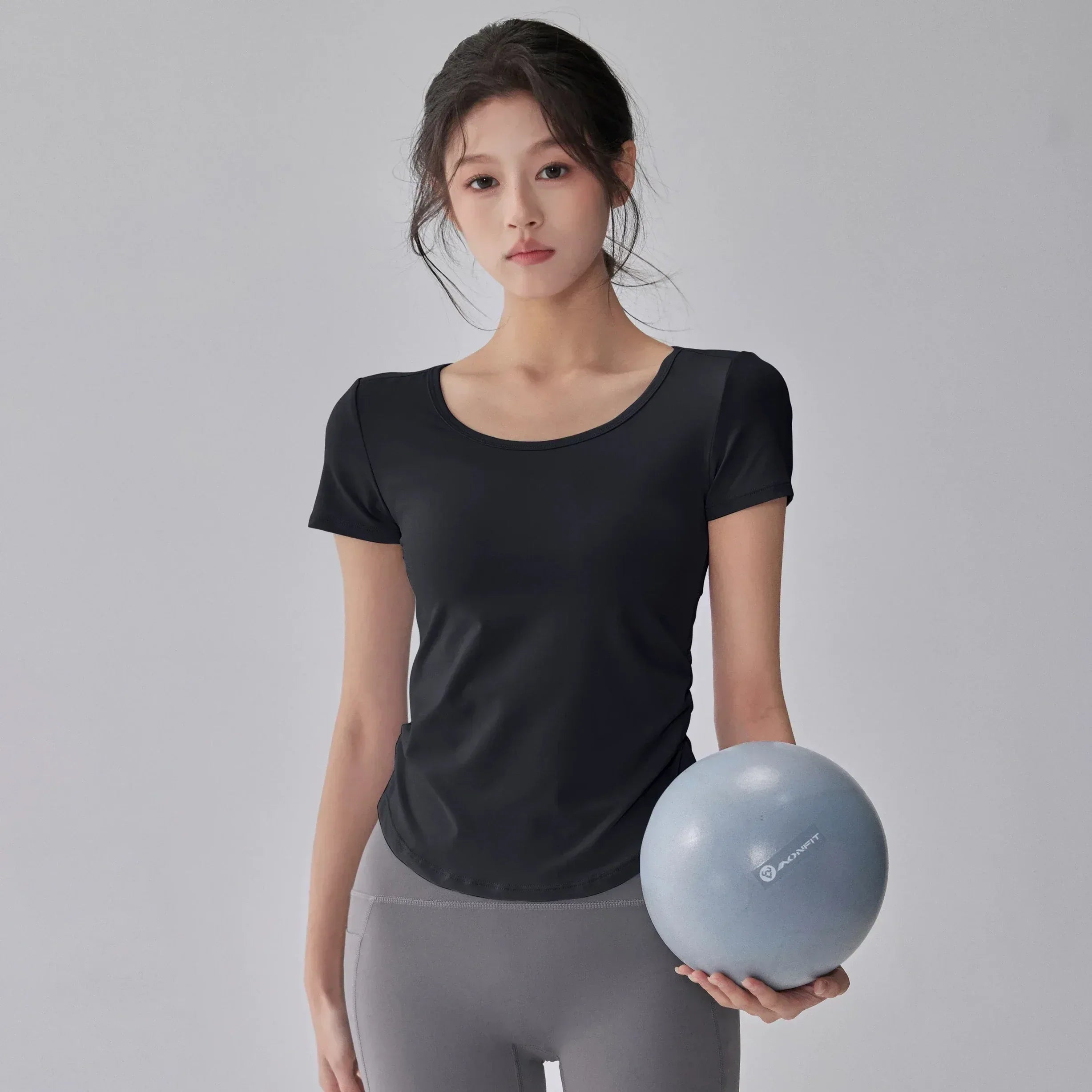 Woman holding a blue exercise ball against a gray background