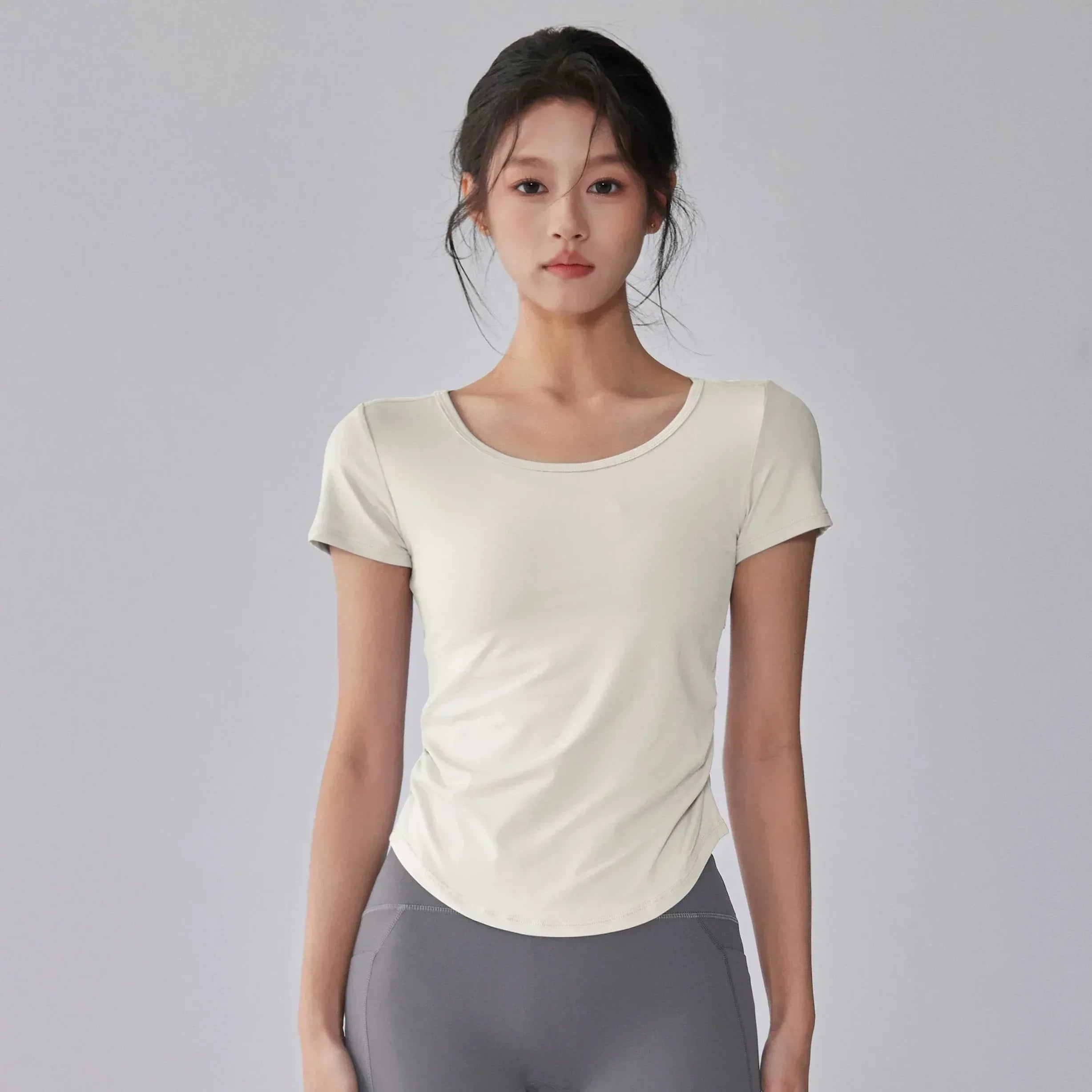 Woman wearing a white t-shirt and gray leggings on a gray background