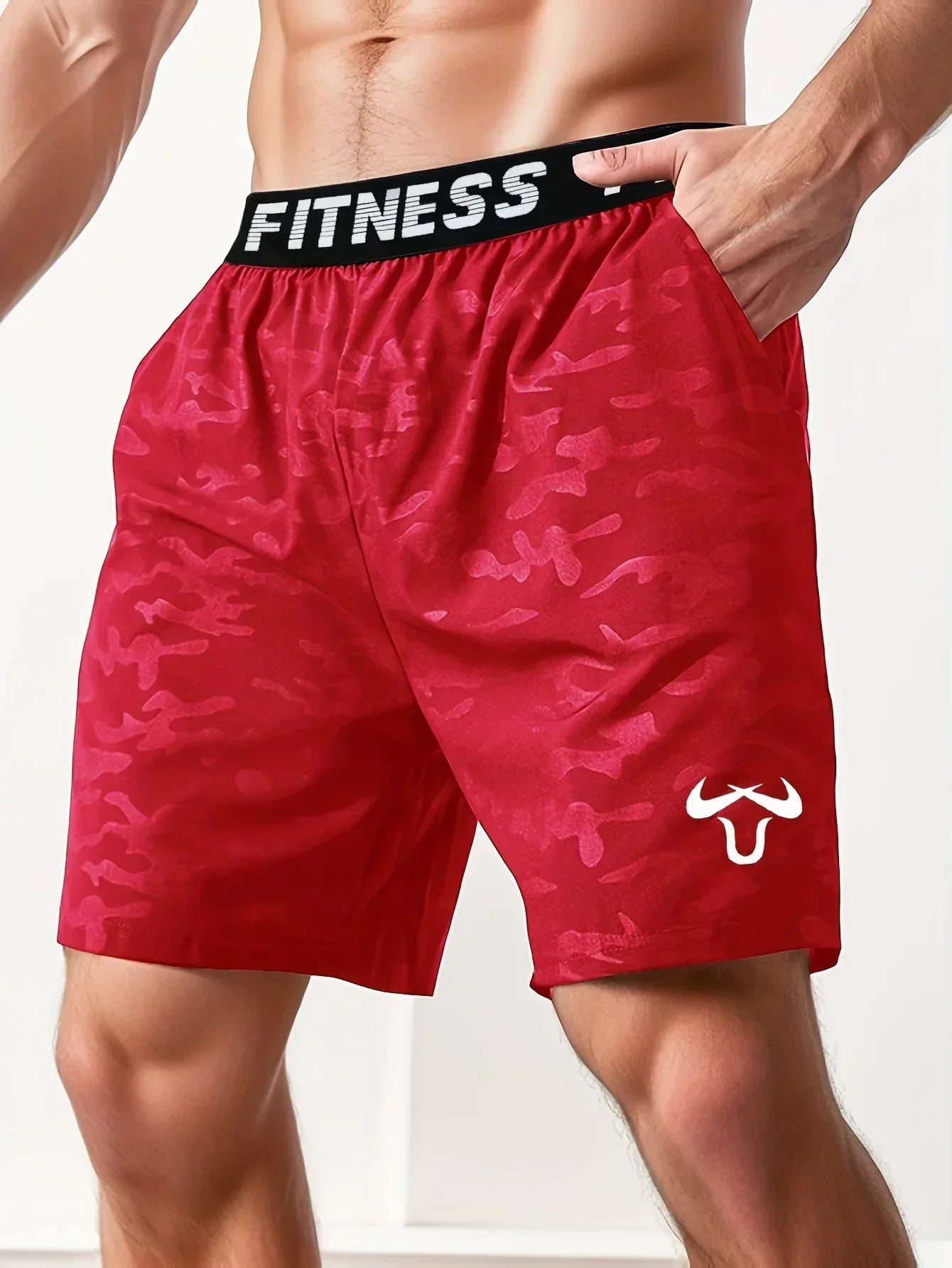 Red camouflage shorts with 'Fitness' waistband on a person against a white background