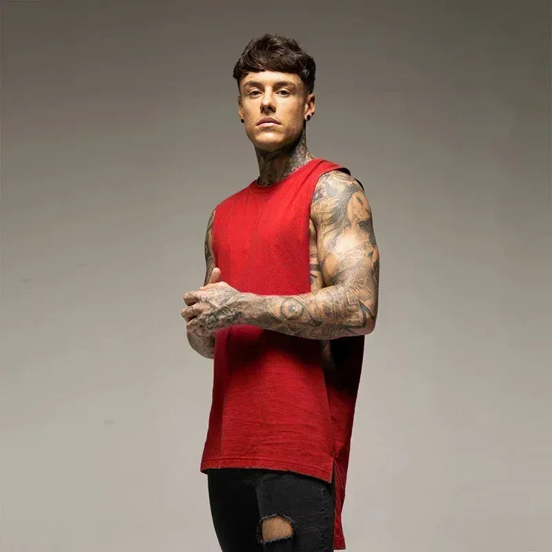 Man wearing a red sleeveless shirt with tattoos on a gray background