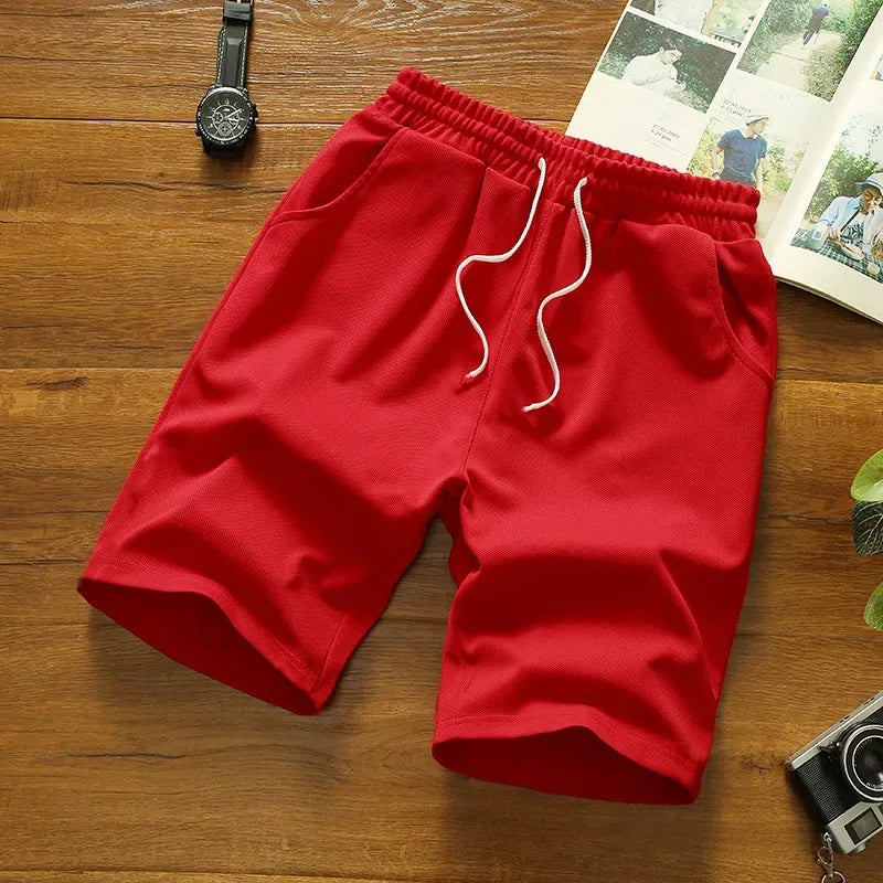 Red shorts on a wooden surface with a watch and photo album in the background