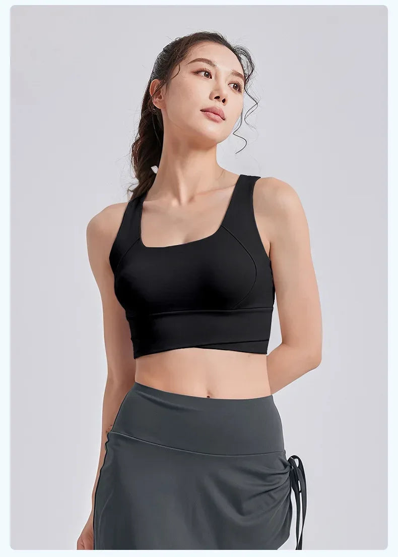 Woman wearing a black sports bra and gray leggings on a light gray background
