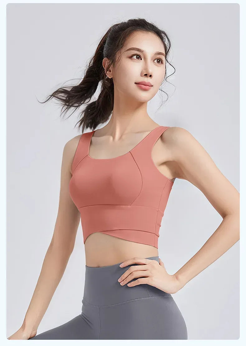 Woman wearing a pink sports bra and gray leggings on a light gray background