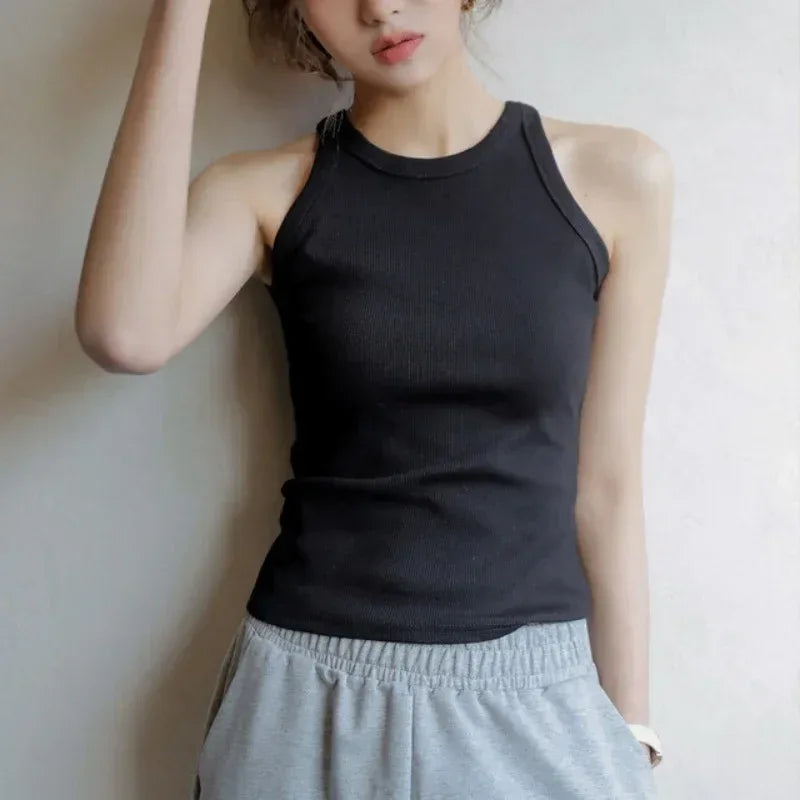 Person wearing a black tank top and gray sweatpants against a plain background